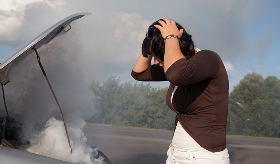 Woman looking at smoking car engine