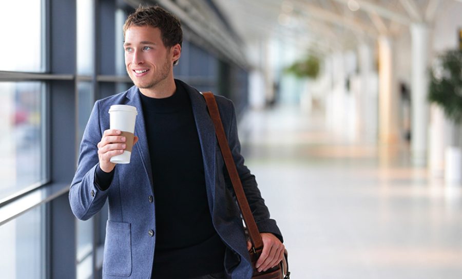 Businessman drinking coffee walking in airport
