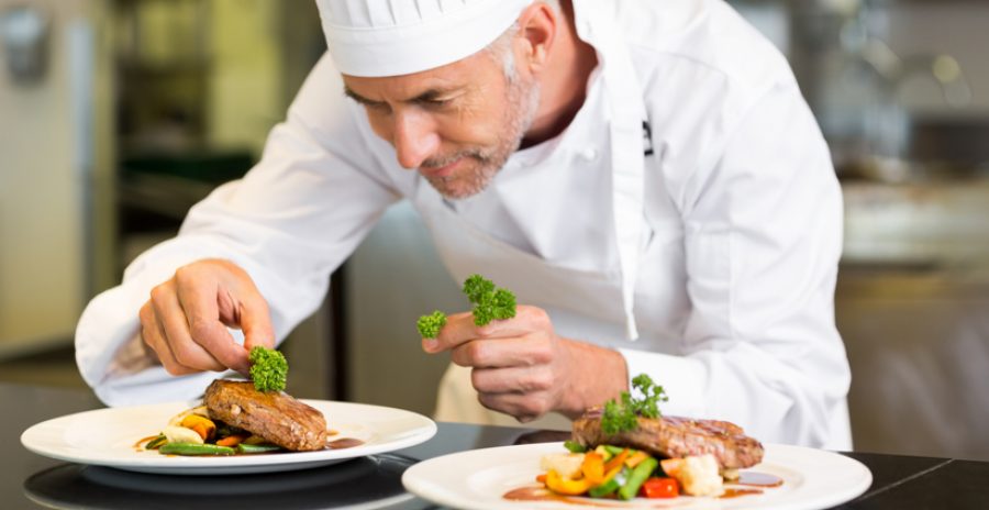 Closeup of a concentrated male chef garnishing food in the kitchen