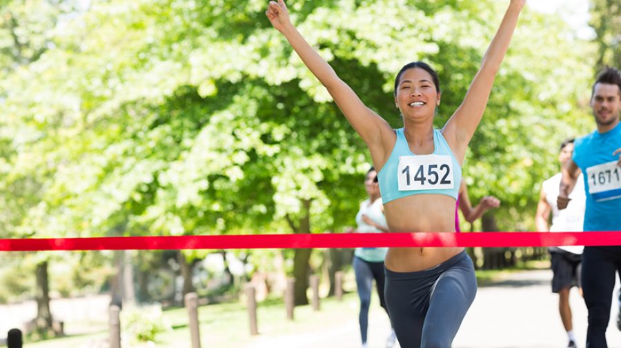 Female marathon winner with arms raised crossing finish line