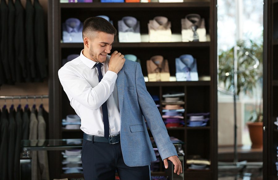 Junger Mann probiert Anzug im Geschäft an