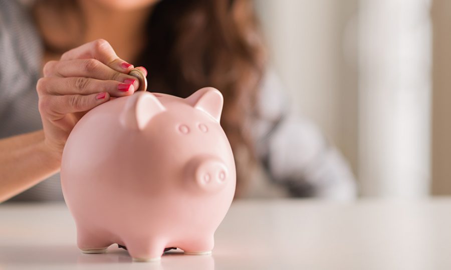 Woman Putting Coin In Piggy Bank