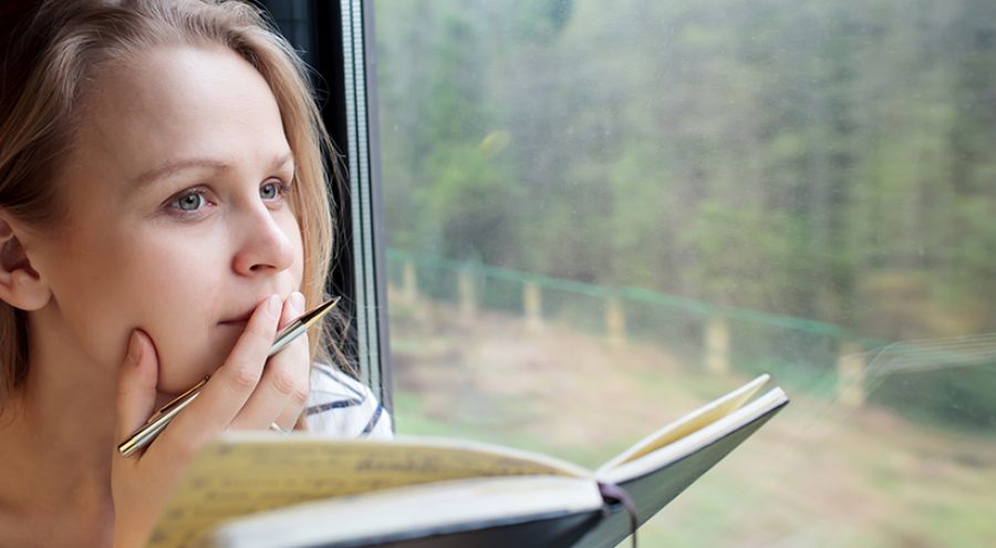 Young woman on a train writing notes