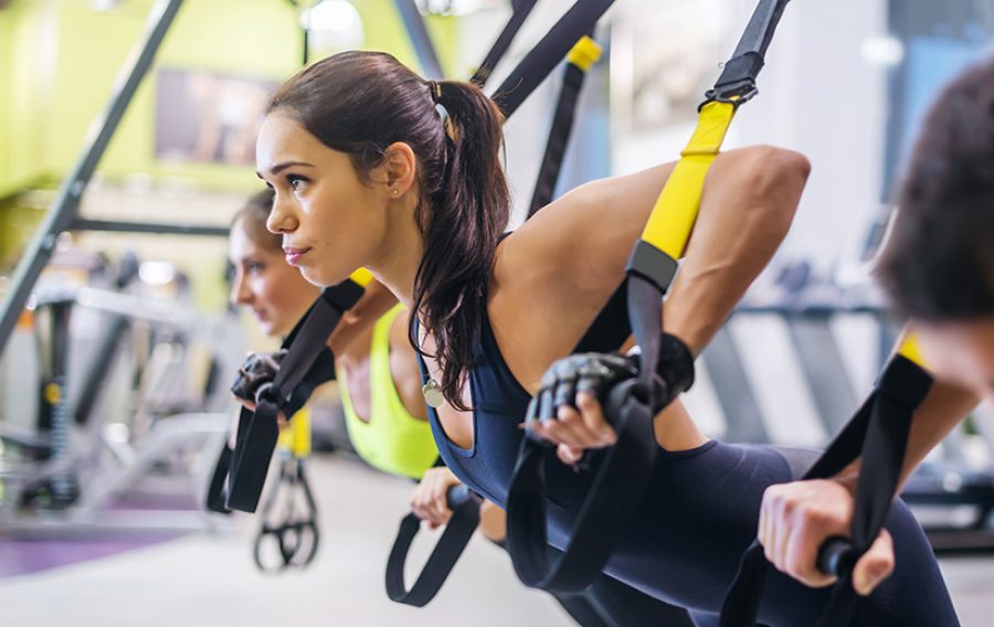 Women doing push ups training arms with trx fitness straps in the gym Concept workout healthy lifestyle sport.
