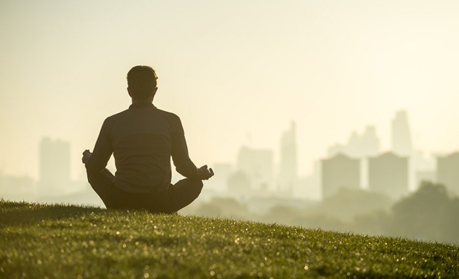 Silhouette of a man sitting in the lotus position meditating on