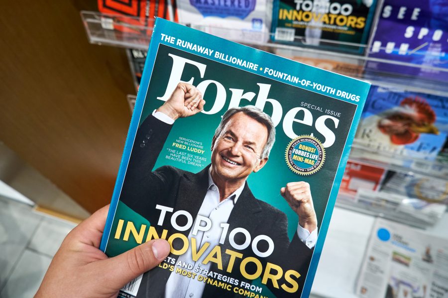 Forbes magazine in a hand.