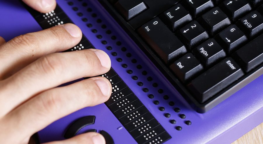 Person nutzt Braille-Zeile von Computer-Tastatur